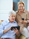 Modern mobility. a happy elderly man using a digital tablet while his wife reads a text message on her cellphone. Royalty Free Stock Photo