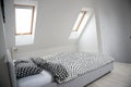 Modern monochrome design home interior of bedroom room in mansard with wooden bed and elegant accessories.