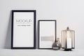 Modern monochrome interior with black mockup poster frame, candle and elegant accessories