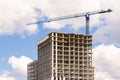 Modern monolithic construction of houses against the blue sky. Single construction tower crane during the construction of a Royalty Free Stock Photo