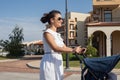 Modern mother on a city street pushing a pram (baby stroller). Royalty Free Stock Photo