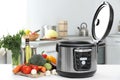 Modern multi cooker and products on table in kitchen. Space for