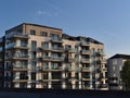 Modern multi-family apartment building in luxury quality with balconies with glass railings in the evening sun with blue sky. Royalty Free Stock Photo