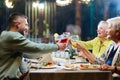 A modern multi generational family, including grandparents and a grandchild, raises a toast during a joyful dinner