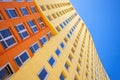 Modern multi-storey building with many glass windows standing against background of blue sky and sun. Residential Royalty Free Stock Photo