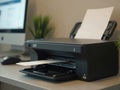 A Modern Multifunction Printer Printing Documents Beside a Computer on a Desk in a Well-Lit Workspace Royalty Free Stock Photo