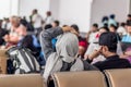 Modern muslim islamic asian couple sitting and waiting for flight departure at international airport terminal