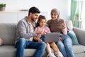 Modern muslim parents teaching their daughter using laptop computer, sitting together on sofa at home Royalty Free Stock Photo