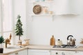 Modern new bright kitchen interior with white furniture and a dining table. gas stove with kettle and pan Royalty Free Stock Photo