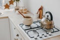 Modern new bright kitchen interior with white furniture and a dining table. gas stove with kettle and pan Royalty Free Stock Photo