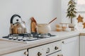 Modern new bright kitchen interior with white furniture and a dining table. gas stove with kettle and pan Royalty Free Stock Photo