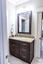 A modern new construction small guest bathroom with espresso cabinets, granite countertops, a tile floor and a mirror Royalty Free Stock Photo