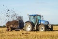 Modern New Holland tractor Tractor spreading manure on fields