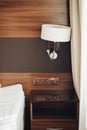 Modern night lamp and bedside table with sockets near bed surrounded by luxury hotel interior
