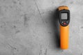 Modern non-contact infrared thermometer on grey stone background, top view. Space for text