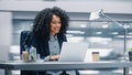 Modern Office: Black Businesswoman Sitting at Her Desk Working on a Laptop Computer. Smiling Succe Royalty Free Stock Photo