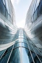 Modern office building with futuristic design, bottom view of exterior and blue sky. Geometric wave facade with glass and steel. Royalty Free Stock Photo