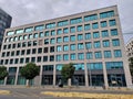 Modern office building with grey facade and many small windows reflecting the cloudy sky in the background Royalty Free Stock Photo