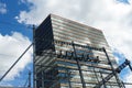 Modern office building near a train station the contact line and their supporting frames are in the foreground.