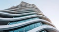 Modern office building with wavy futuristic design, low angle view of abstract curve lines on sky background. Geometric facade