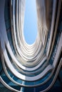 Modern office building with wavy futuristic design, low angle view of curve lines and sky. Abstract geometric facade with glass