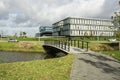 Modern office buildings in a business area in the Netherlands with canal, trees, water, blue sky, white clouds and wharves Royalty Free Stock Photo