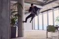 In the modern office, a businessman with a briefcase captivates everyone as he performs thrilling aerial acrobatics Royalty Free Stock Photo