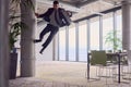 In the modern office, a businessman with a briefcase captivates everyone as he performs thrilling aerial acrobatics Royalty Free Stock Photo