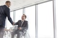 Businessman shaking hands with smiling disabled colleague in boardroom during meeting at office Royalty Free Stock Photo