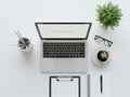 Modern office desk setup overhead view laptop coffee glasses plant notebook pens Royalty Free Stock Photo