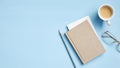 Modern office desk table with notebook, paper note, cup of coffee, pencil, glasses on blue background. Elegant feminine workspace