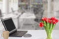 Modern office desk workplace with laptop computer with blank screen mockup on table a cup of coffee and a bouquet of tulips over Royalty Free Stock Photo