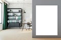 A modern office interior with a white brick wall, a desk with a computer, shelves with binders, and a large blank mockup poster. Royalty Free Stock Photo