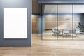 Modern office meeting room with a blank poster frame on the wall, wooden elements, and glass partition, concept of branding space