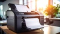 Modern office printer printing documents on a wooden desk near a window. Royalty Free Stock Photo