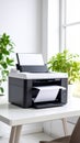 Modern office printer producing paper on a white desk with green plants and natural window light Royalty Free Stock Photo