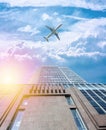 A modern office skyscraper in the morning sun and a white passenger airplane flying over this building Royalty Free Stock Photo
