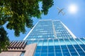A modern office skyscraper and white passenger airplane flying over this building Royalty Free Stock Photo