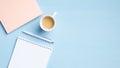 Modern office table with blank notepad, cup of coffee, pink paper notebook, pen on blue background. Minimal style feminine Royalty Free Stock Photo