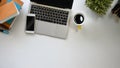 Modern office working desk including a coffee cup, laptop, black blank screen smartphone, potted plant, pencil and books. Royalty Free Stock Photo