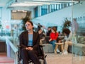 In a modern office, a young businesswoman in a wheelchair is surrounded by her supportive colleagues, embodying the