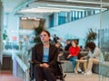 In a modern office, a young businesswoman in a wheelchair is surrounded by her supportive colleagues, embodying the