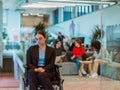 In a modern office, a young businesswoman in a wheelchair is surrounded by her supportive colleagues, embodying the