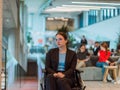 In a modern office, a young businesswoman in a wheelchair is surrounded by her supportive colleagues, embodying the
