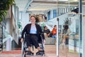 In a modern office, a young businesswoman in a wheelchair is surrounded by her supportive colleagues, embodying the