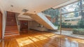 Modern open-plan interior with wooden floors, stairs, and a garden view Royalty Free Stock Photo