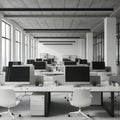 Modern open plan office space with rows of computers and chairs bathed in natural light from large windows Royalty Free Stock Photo