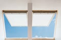 A modern open skylights mansard windows in an attic room against blue sky. Royalty Free Stock Photo