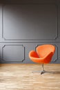 Modern orange armchair in minimal grey living room interior with