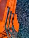 Modern orange plastic and chrome chairs stacked up outdoors.